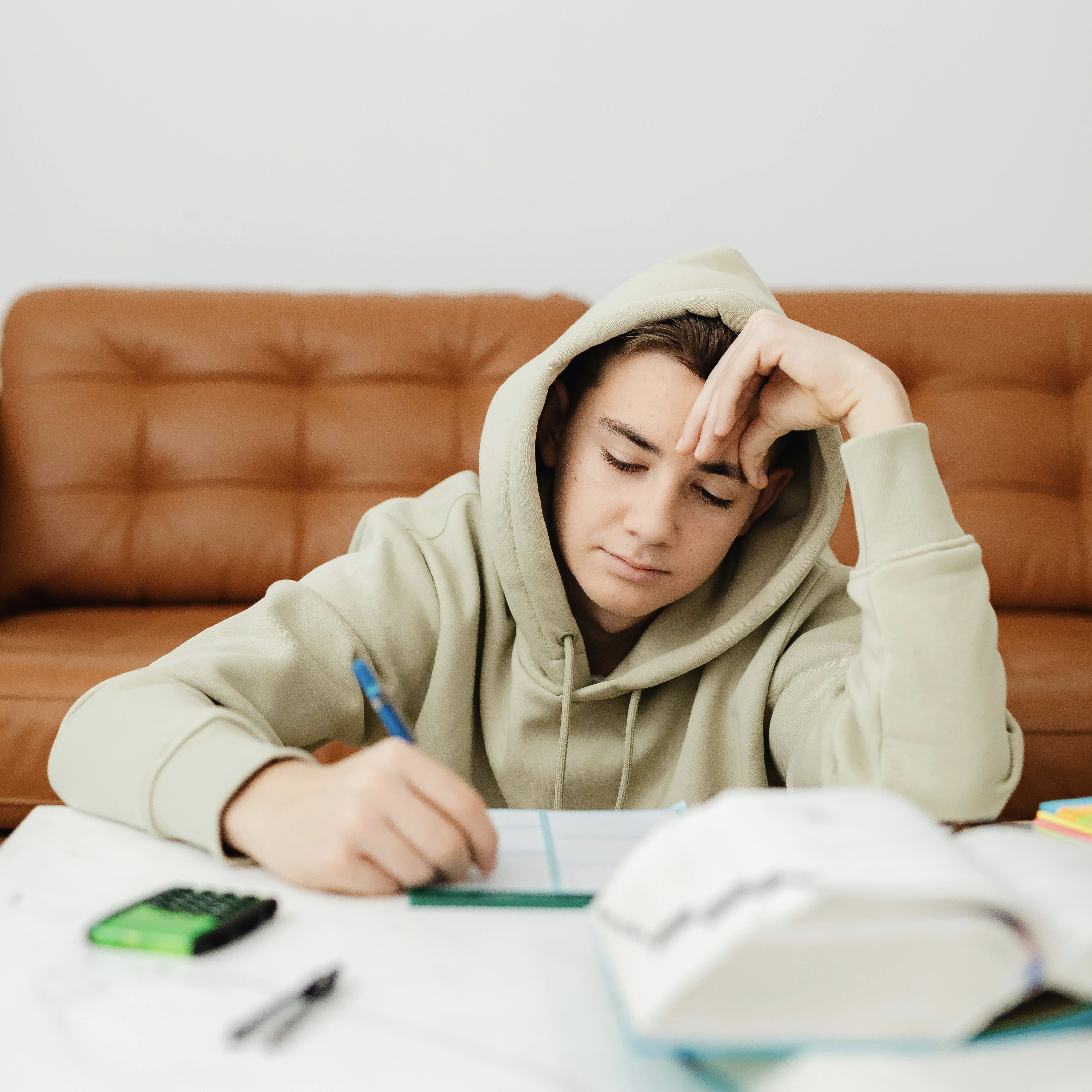 Male student writing and appearing stressed.