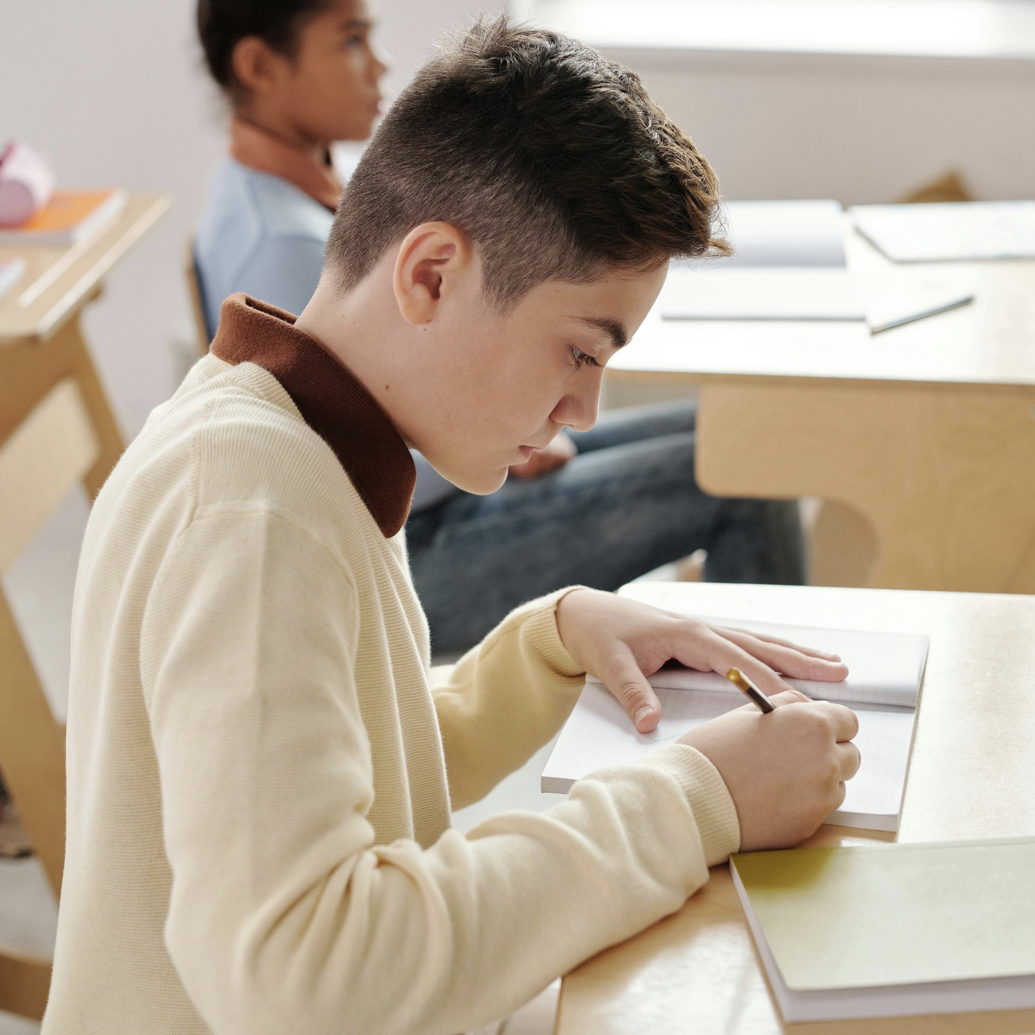 Male student writing in a notebook.