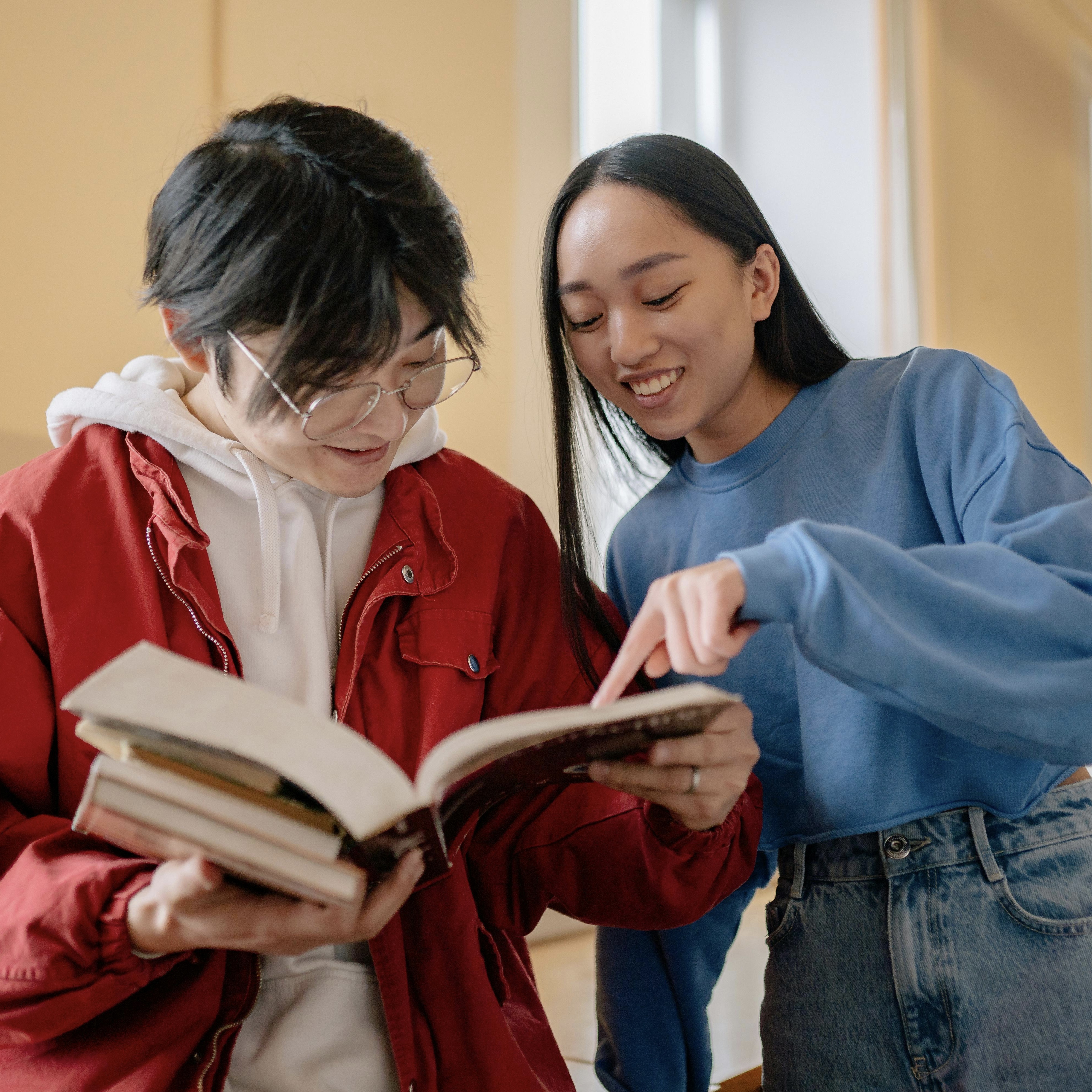 Two female students reading a book.