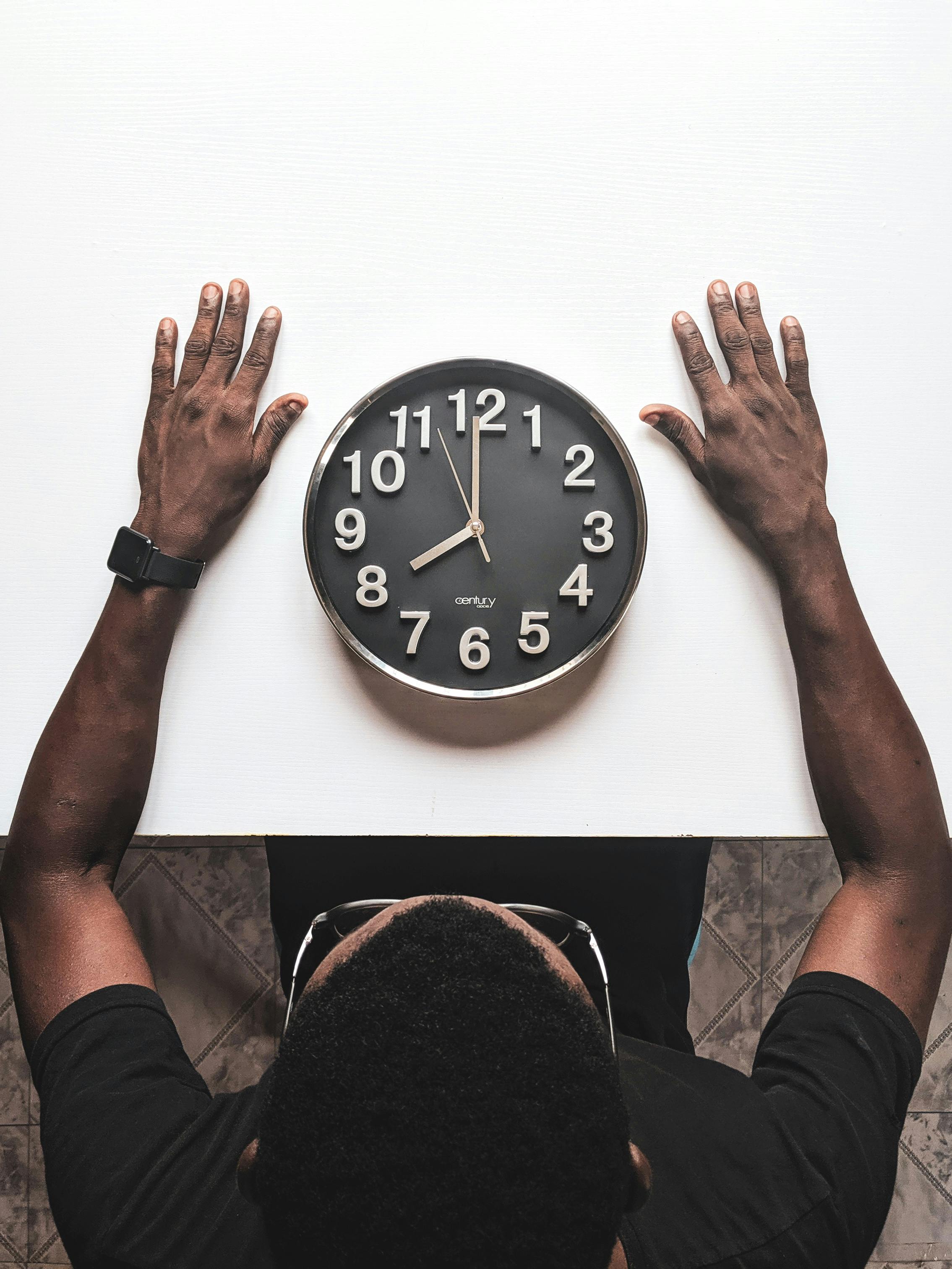 Male student looking down at an analog clock.