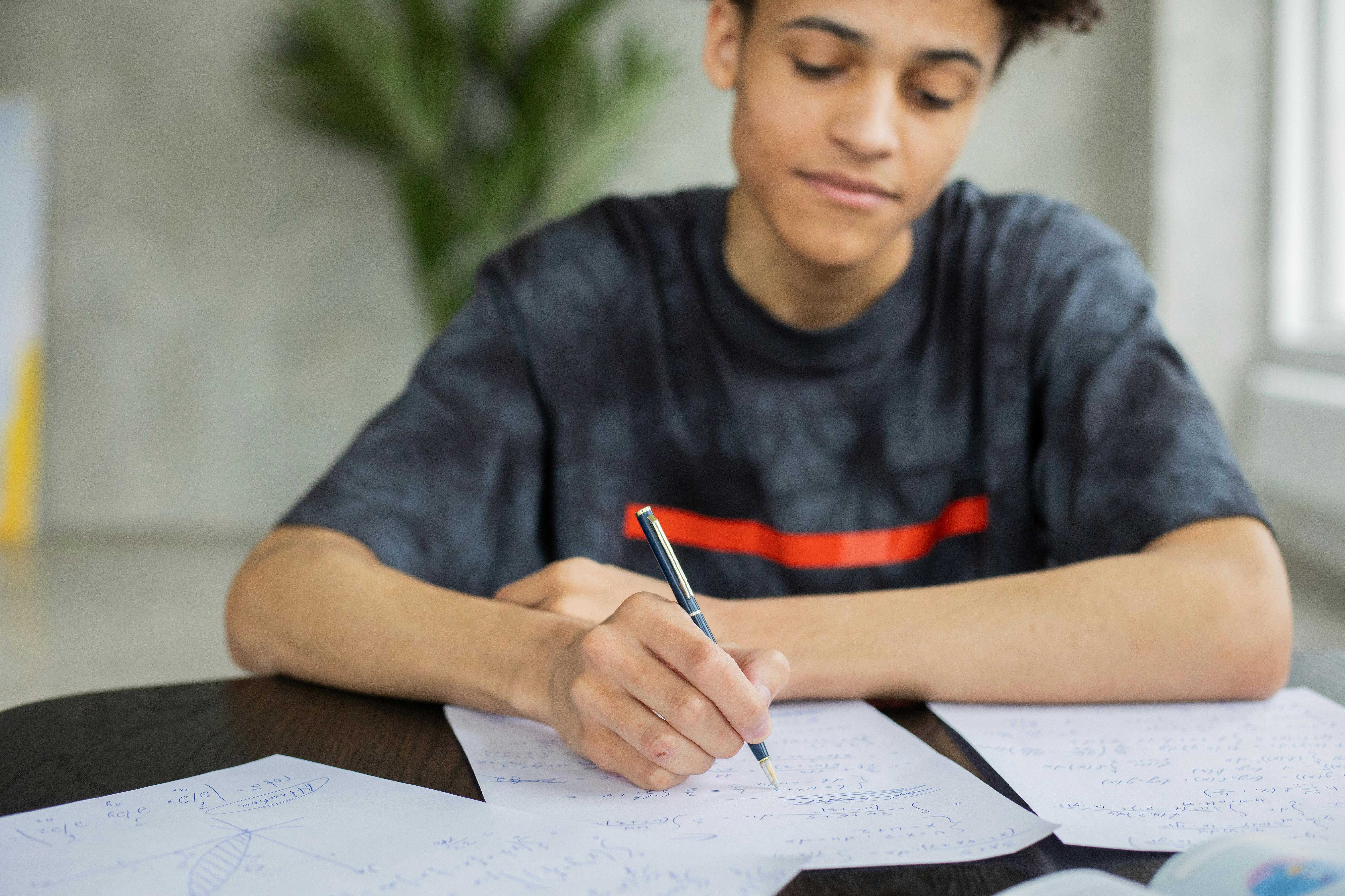 Male student writing on a piece of paper.