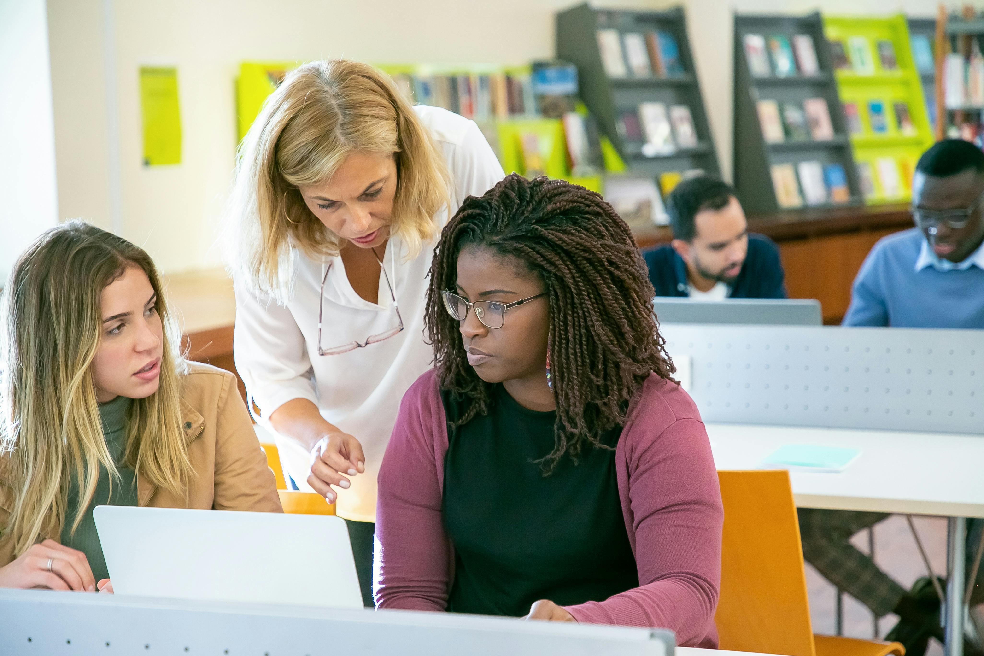 Female educator instructing a female student in a library.