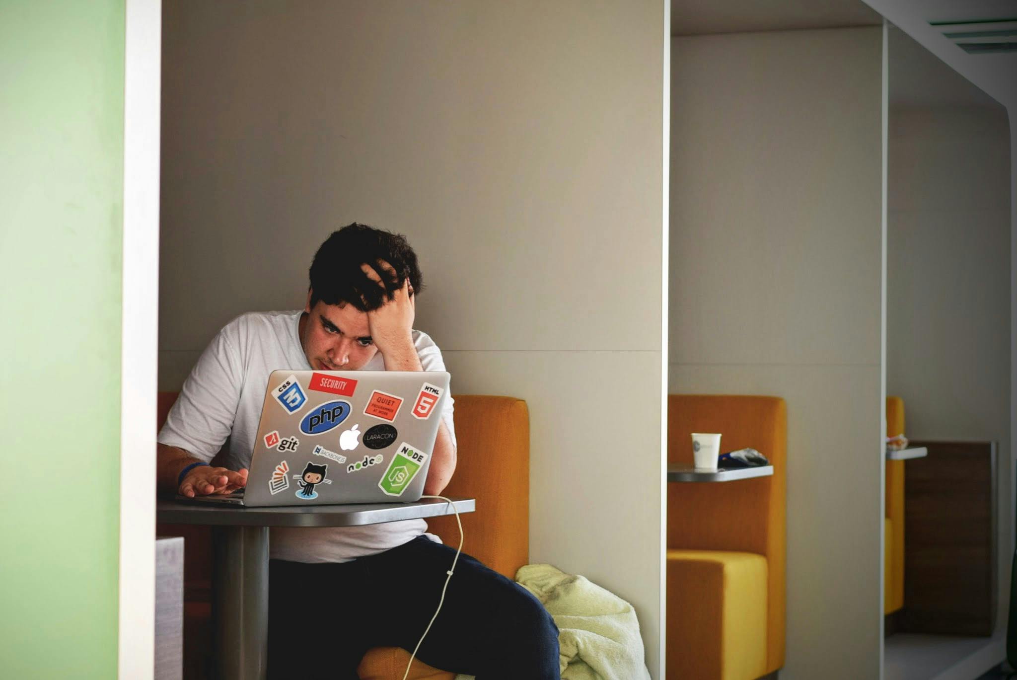 Male student looking at a laptop and appearing stressed.