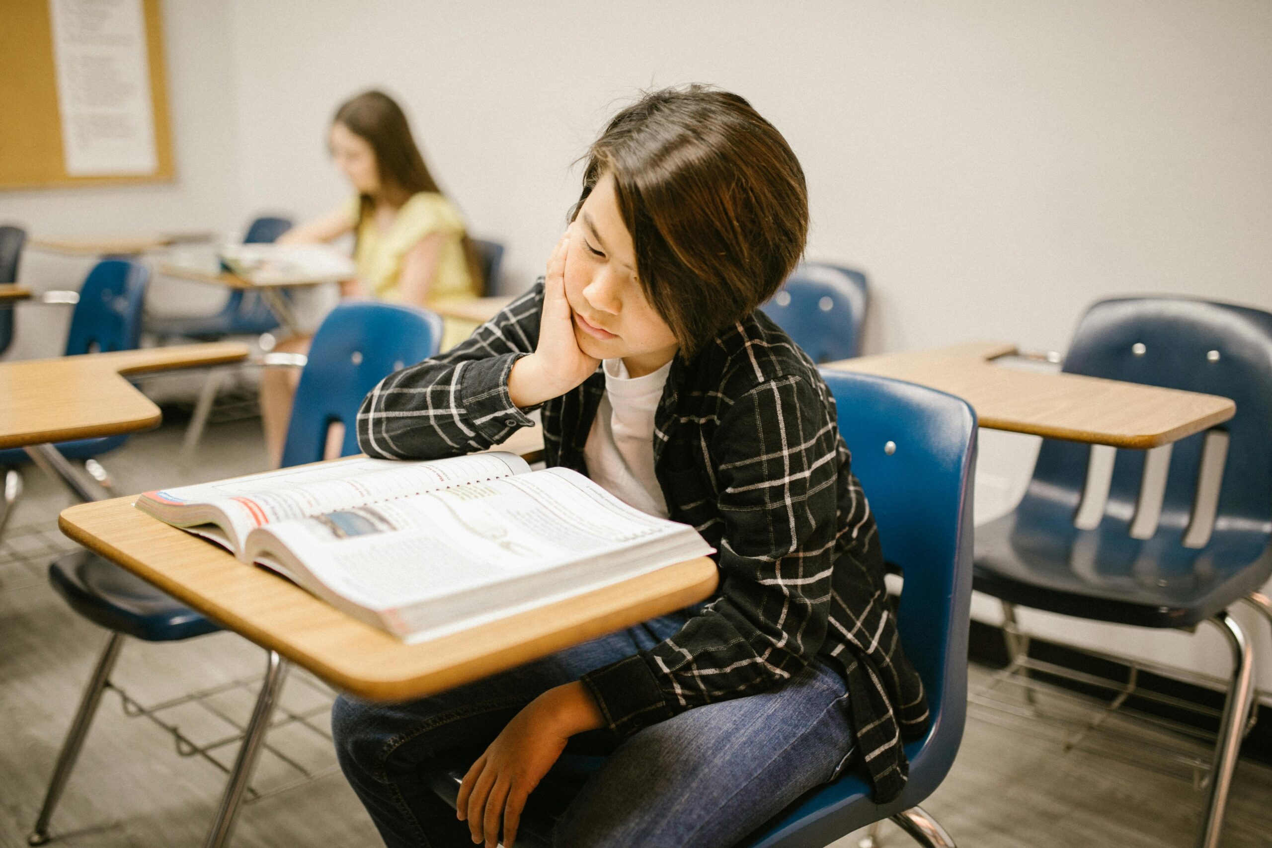 Male student reading a textbook in a classroom.